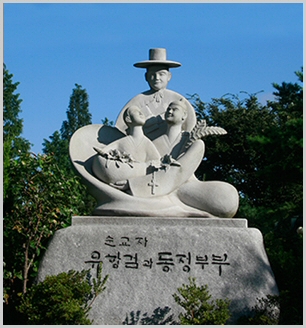 기단에 '순교자 유항검과 동정부부'라 새겨진 석조 기념 조형물로, 갓 쓴 인물과 부부 형상이 조각되어 있다.